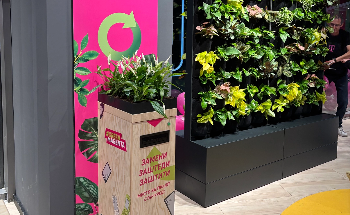 Eine Recyclingbox steht neben einer Wand voller Pflanzen