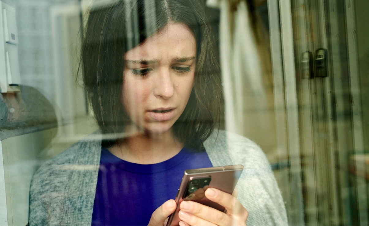 Eine Frau schaut bestürzt auf ihr Smartphone.