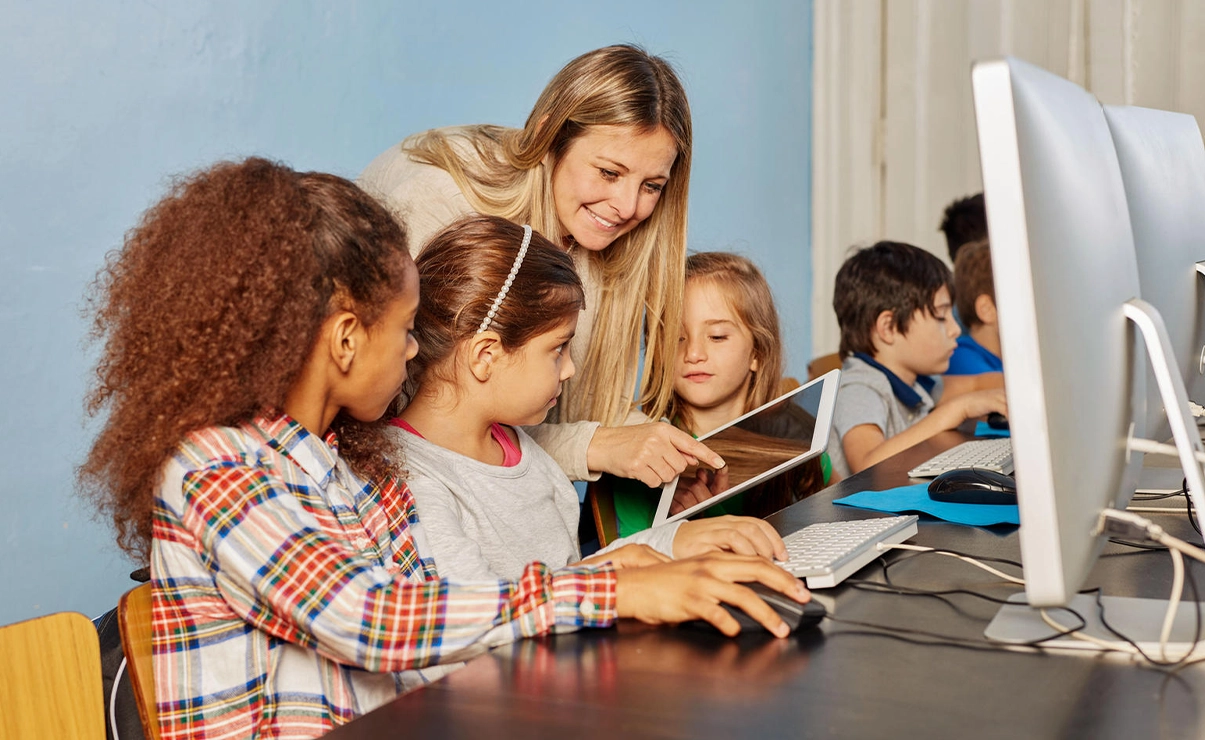 Lehrerin mit Schülerinnen beim EDV Unterricht (Foto)